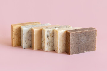 Beige and brown soap bars in a line on light pink close up. Natural herbal product for SPA