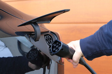 A hand holds a charging cable for an electric car. A view of the charging connector.