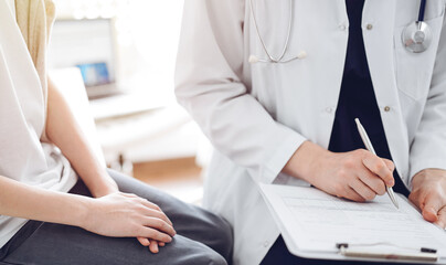 Doctor and child patient. The physician is holding clipboard and writing in medical record form near a boy. The concept of ideal health in medicine