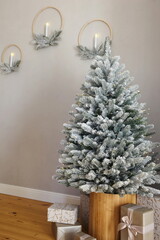 Christmas tree in the snow in an apartment with gray walls