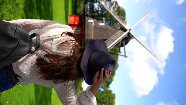 Woman with hat and backpack looking at historic windmill in Kastellet, Denmark. Vertical