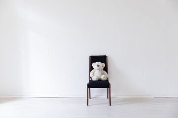 Black chair with bear toy in white room interior - obrazy, fototapety, plakaty
