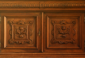 Old vintage wardrobe furniture with ornamental doors and retro colors of wooden surfaces close up