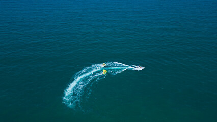 Naklejka premium Aerial view of a group of people riding a banana boat and falling into the ocean. Water activities and sports to enjoy while on holiday. Happy people on a banana in the ocean