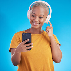 Woman, headphones and phone listening to music, audio streaming service and social media on a blue...