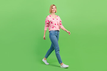 Full body photo of pretty young girl walking going dressed stylish pink strawberry print outfit isolated on green color background