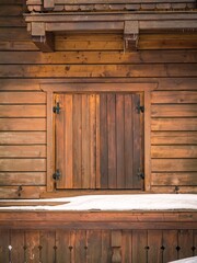 Closed shutters on the window of a wooden log house from the outside, winter