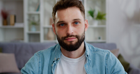 Portrait face of smiling man with blue eyes and beard sitting inside office, posing and looking...