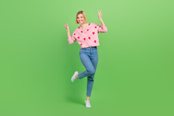 Full body photo of pretty young girl showing double v-sign hi wear trendy pink strawberry print outfit isolated on green color background