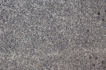 Abstract textured background graphic element. Close up of rough, pebbly, concrete, aggregate footpath with copy space. Many visible, jagged stones of different sizes and grunge style dark blotches.