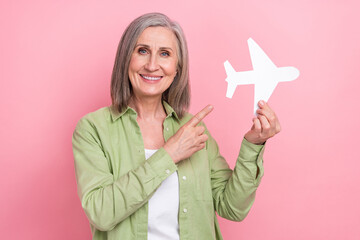Photo of satisfied lovely retired lady wear green trendy clothes hold airplane recommend buy tickets isolated on pink color background