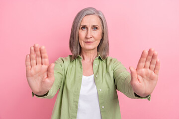 Photo of serious confident elderly woman wear green trendy clothes demonstrate two arms keep...