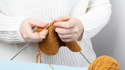 Woman in white sweater knitting yellow yarn clothes