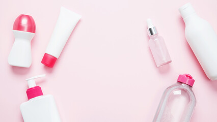 Cosmetic beauty products on pink background. Bottles and tubes with branding mock up. Skin care and beauty concept. Top view, flat lay, copy space