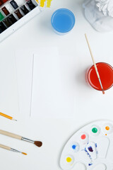 Watercolor and other artistic accessories on a white background. Artist's desk workplace. Top view, copy space, flatlay