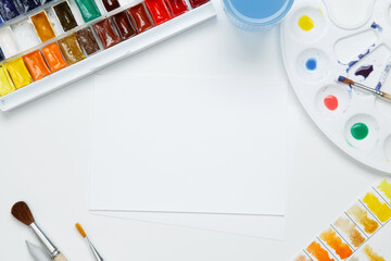 Watercolor and other artistic accessories on a white background. Artist's desk workplace. Top view, copy space, flatlay