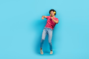 Fototapeta na wymiar Full body photo of handsome young male dancer discotheque promotion earphones dressed stylish pink outfit isolated on blue color background
