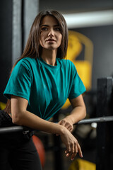 Beautiful athletic girl fitness model leans against bench press bar with weight