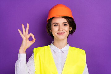 Photo of optimistic nice brunette hair lady show okey wear builder uniform isolated on vivid purple color background
