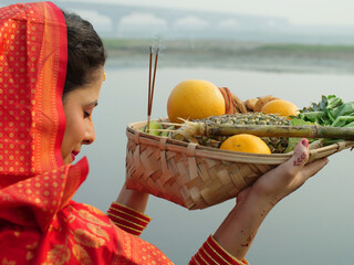 An Indian devotee in traditional attire offers prayers to the sun during the Chhath festival  ...