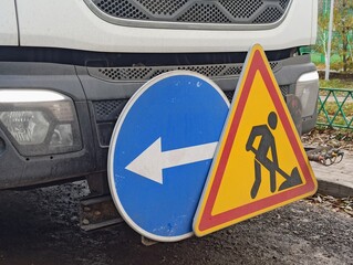  Blue arrow sign and man with shovel sign on the front of a truck.
