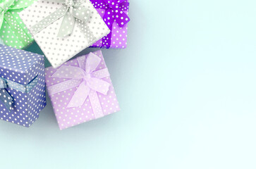 Pile of a small colored gift boxes with ribbons lies on a violet background. Minimalism flat lay top view.