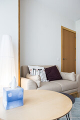 Living room with armchair, cushions, round table with handkerchiefs, floor lamp and lots of natural light. Concept of minimalism and simplicity. Copy space. Vertical