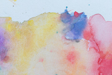 Macro close-up of abstract colorful watercolors with splashes, splatters and stains. Textured white aquarelle paper background with copy space.