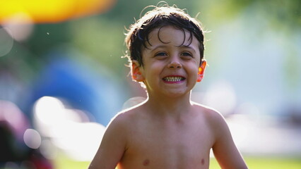 Portrait of small boy sitting on grass outside after swimming at the pool, relaxed and happy expression, warm summer day