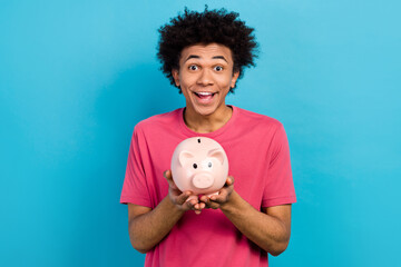 Photo of funky cheerful man wear pink trendy clothes hands hold piggy bank collect cash banknotes...