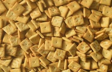 A lot of small cookies are square shaped. A pattern of a yellow salt cracker. Background image with salted pastry