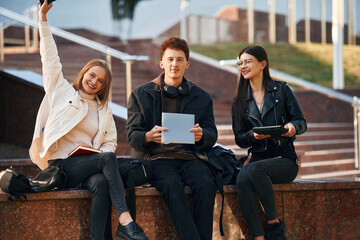 With notepad. Three young students are outside the university outdoors