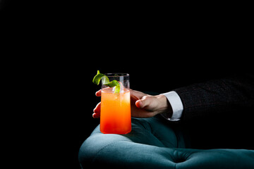 bright tropical cocktail with lime peel and gradient color in a transparent glass, side view
