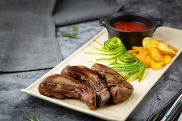 side view of meat ribs with avocado, chips and ketchup on a white plate