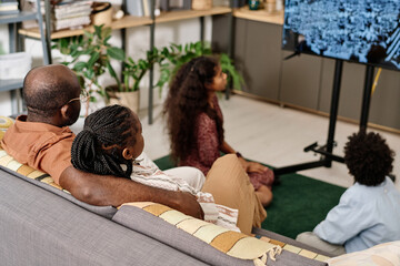 Black family watching Martin Luther King Jr speaking in front of crowd on tv