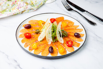 Sliced red fish slices with herbs, cherry tomatoes and white bread croutons