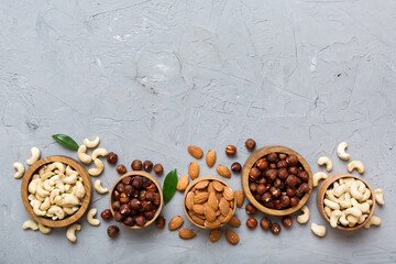 Assortment of nuts in wooden bowl on colored table. Cashew, hazelnuts, walnuts, almonds. Mix of nuts Top view with copy space