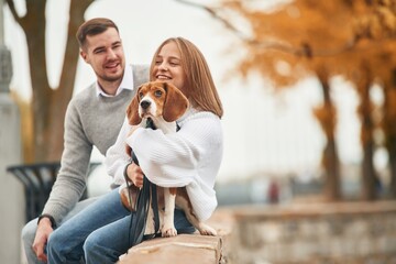 Lovely couple are with their cute dog outdoors