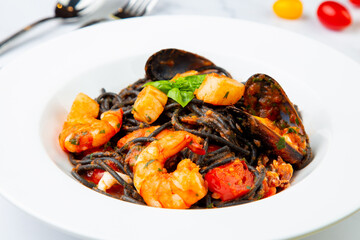 black noodles with mussels, shrimp, tomatoes and herbs side view