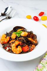 black noodles with mussels, shrimp, tomatoes and herbs side view