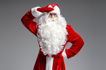 Portrait of Santa Claus with white  looking at camera searching someone  isolated on gray background    