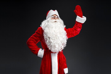 Santa Claus waving hand looking away isolated on black background. Marry Christmas, advertisement concept