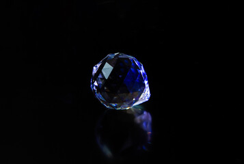 A close-up with a precious stone shining on a black background. A large isolated diamond...