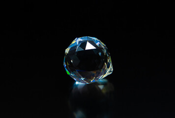 Fototapeta premium A gemstone crystal sparkling on a dark background. Diamond imitation on a black background