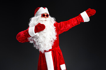 Funny man wearing Santa Claus costume  and stylish sunglasses dancing celebration winter holidays isolated on black background. Marry Christmas concept 