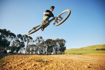 Jump, mountain bike and man outdoor in nature for extreme sports, training or workout. Sky, air or...