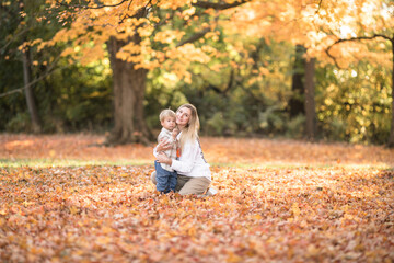 Happy young mother and two brothers walking in the autumn forest. Autumn outdoor activity for...
