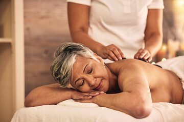Woman, spa and stone massage for healing back muscle, skincare treatment and holistic therapy at...