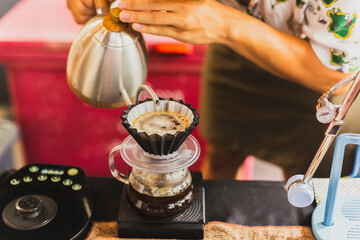 Professional barista preparing coffee using chemex pour over coffee maker and drip kettle.