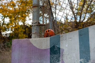 halloween pumpkin discarded behind a chain link fence in autumn